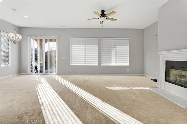 unfurnished living room with light carpet and ceiling fan with notable chandelier