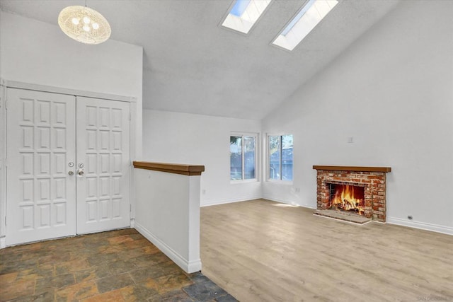 entryway featuring a brick fireplace, dark wood-type flooring, high vaulted ceiling, and a skylight