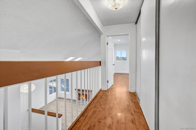 hall featuring a textured ceiling and light hardwood / wood-style flooring