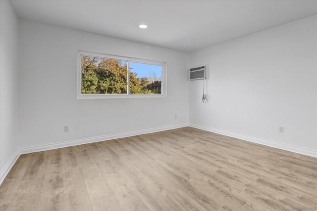 empty room with a wall mounted AC and light hardwood / wood-style floors