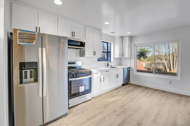 kitchen with sink, stainless steel appliances, white cabinets, and light wood-type flooring