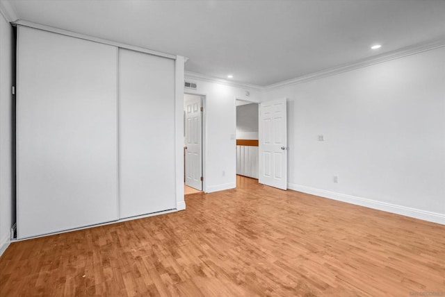 unfurnished bedroom featuring crown molding, light hardwood / wood-style floors, and a closet