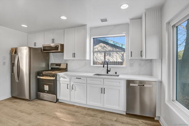 kitchen with white cabinetry, appliances with stainless steel finishes, sink, and a wealth of natural light