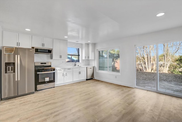 kitchen with stainless steel appliances, sink, light hardwood / wood-style floors, and white cabinets