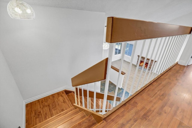 stairway with wood-type flooring, a textured ceiling, and a notable chandelier