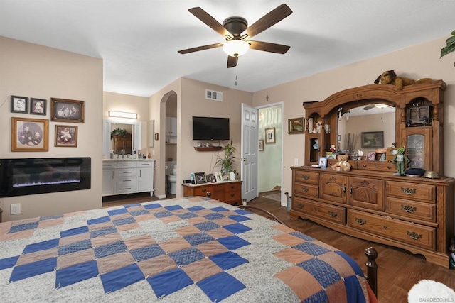 bedroom with ceiling fan, connected bathroom, and dark hardwood / wood-style flooring