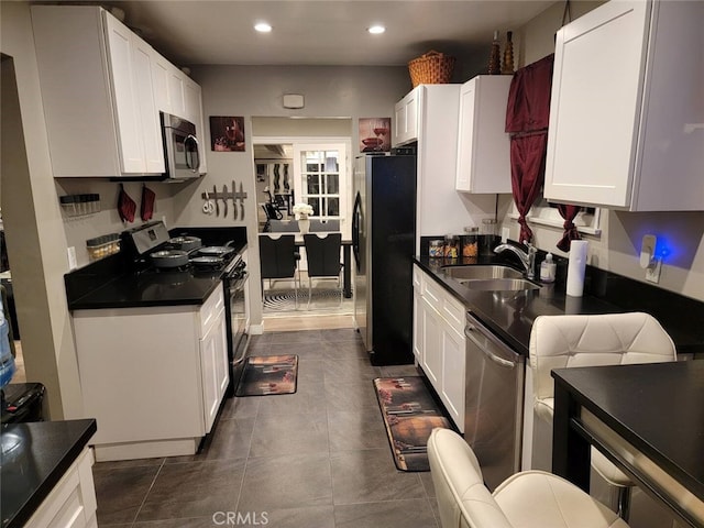 kitchen featuring dark tile patterned floors, white cabinetry, appliances with stainless steel finishes, and sink