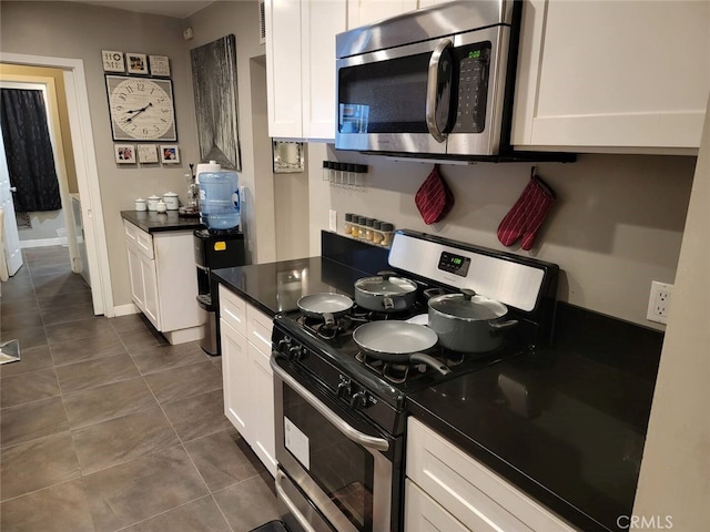 kitchen featuring white cabinetry, appliances with stainless steel finishes, and dark tile patterned flooring