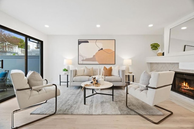 living room with a tile fireplace and light hardwood / wood-style floors