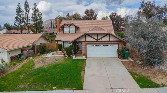 tudor house featuring driveway, a garage, a tile roof, fence, and a front yard