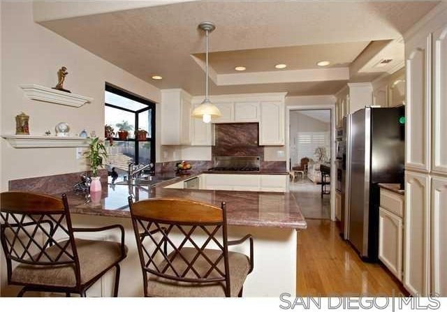 kitchen featuring hanging light fixtures, sink, stainless steel fridge, and kitchen peninsula