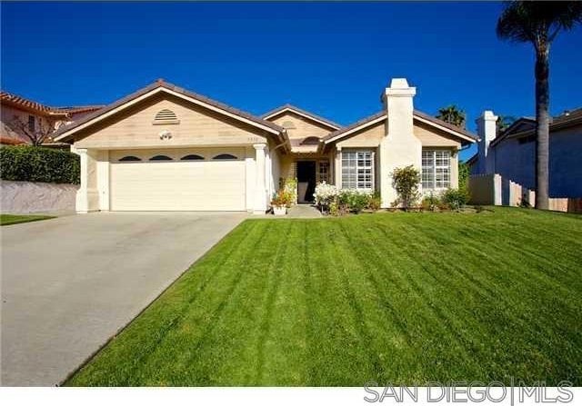 ranch-style house with a garage and a front lawn