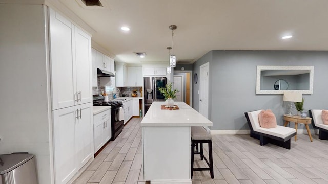 kitchen featuring black gas range oven, decorative light fixtures, stainless steel fridge, white cabinets, and a center island