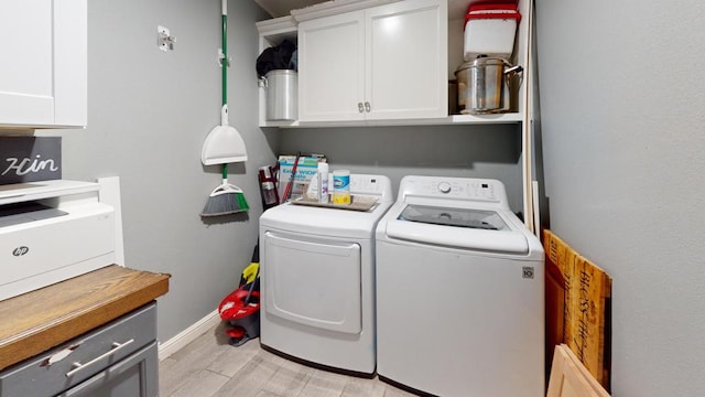 clothes washing area featuring light hardwood / wood-style floors, washing machine and dryer, and cabinets