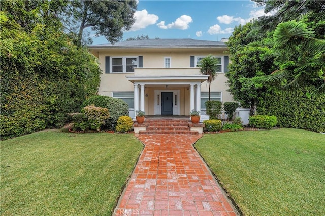 view of front of property featuring covered porch, stucco siding, and a front lawn