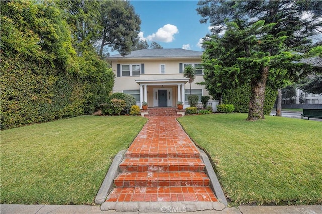 colonial inspired home with a front yard and stucco siding