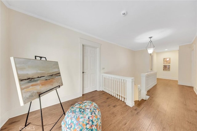 sitting room with wood finished floors, baseboards, ornamental molding, and an upstairs landing
