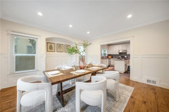 dining area featuring a decorative wall, visible vents, and wainscoting