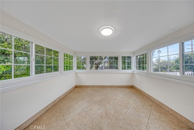unfurnished sunroom featuring baseboards and tile patterned flooring
