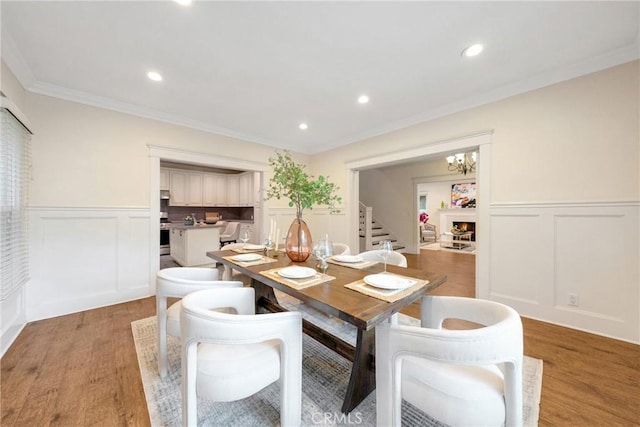dining room featuring a decorative wall, wainscoting, and light wood-style floors