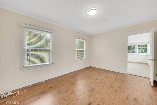 unfurnished room with baseboards, light wood-type flooring, and ornamental molding