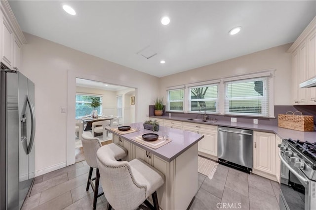 kitchen featuring a center island, white cabinets, a sink, a kitchen breakfast bar, and stainless steel appliances
