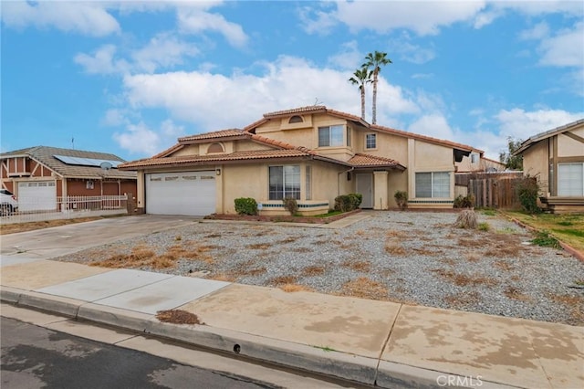 view of front facade with driveway, a garage, a tiled roof, fence, and stucco siding