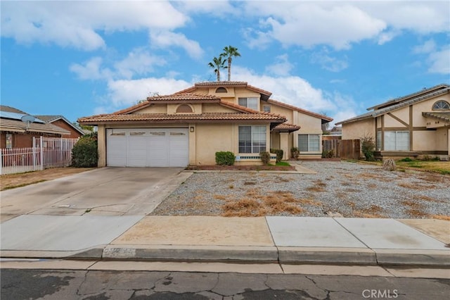 view of front facade with an attached garage, fence, a tile roof, concrete driveway, and stucco siding