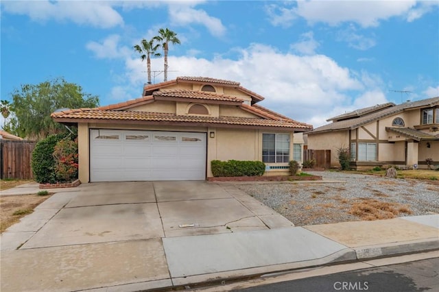 mediterranean / spanish-style home featuring a tile roof, stucco siding, fence, a garage, and driveway