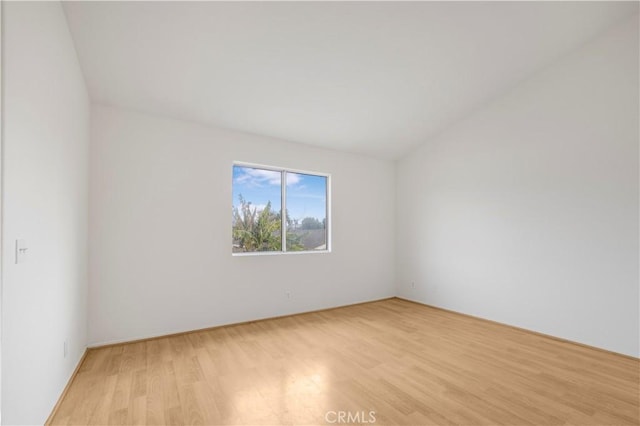 empty room featuring lofted ceiling and light hardwood / wood-style floors