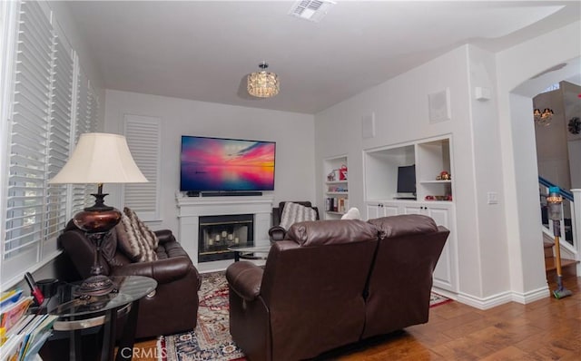 living room featuring built in shelves and wood-type flooring