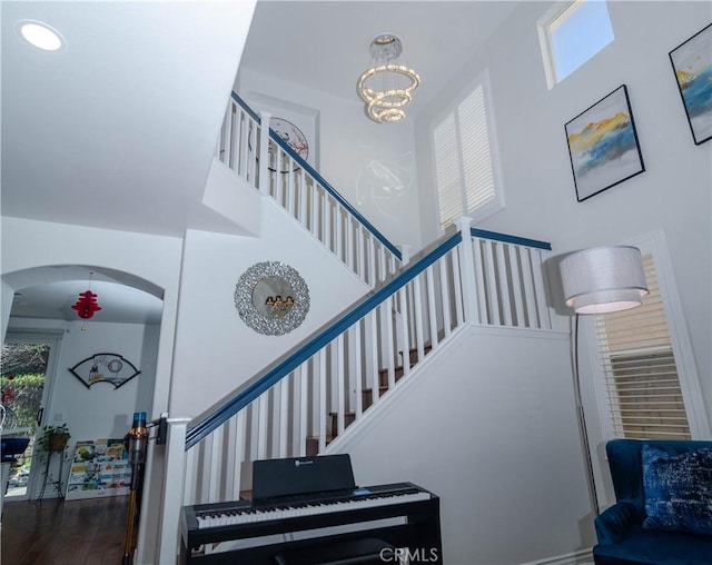 staircase with hardwood / wood-style flooring, a notable chandelier, and a towering ceiling