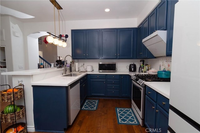 kitchen featuring appliances with stainless steel finishes, sink, blue cabinetry, pendant lighting, and kitchen peninsula