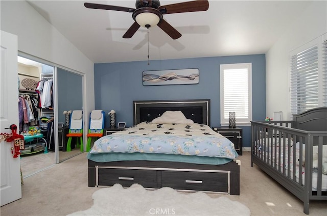 bedroom with ceiling fan, light carpet, and a closet