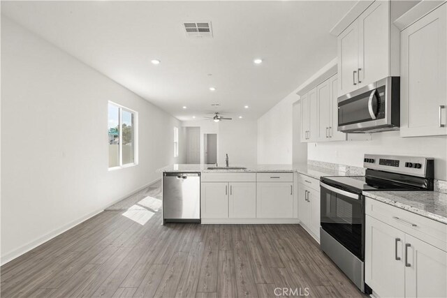 kitchen with white cabinetry, stainless steel appliances, kitchen peninsula, and sink