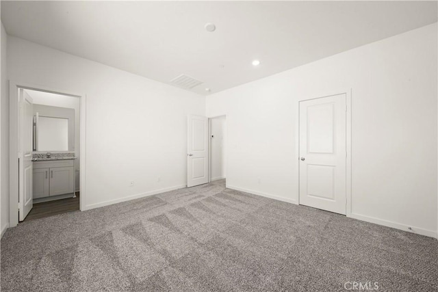 unfurnished bedroom with connected bathroom, sink, and carpet flooring