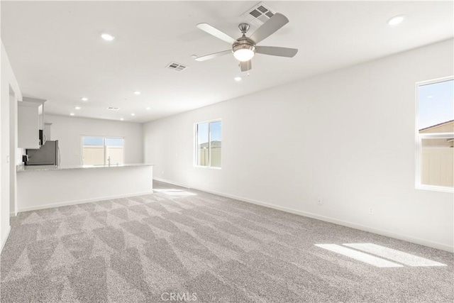 carpeted empty room with ceiling fan and a healthy amount of sunlight