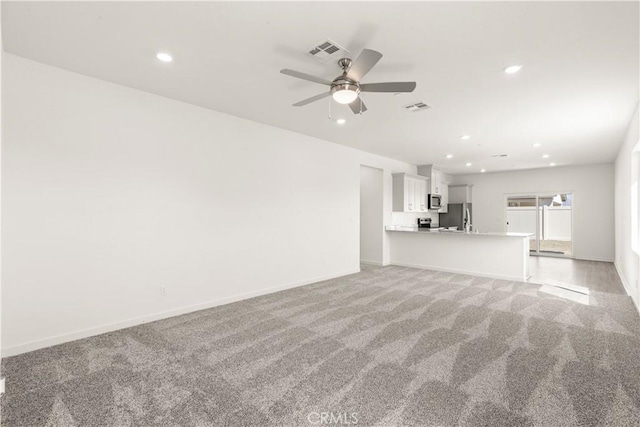 unfurnished living room with light colored carpet and ceiling fan