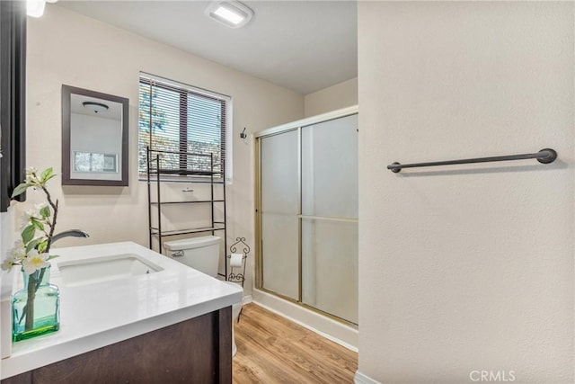 bathroom featuring toilet, wood finished floors, a shower stall, and vanity