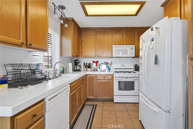 kitchen featuring white appliances, tile counters, sink, and light tile patterned floors