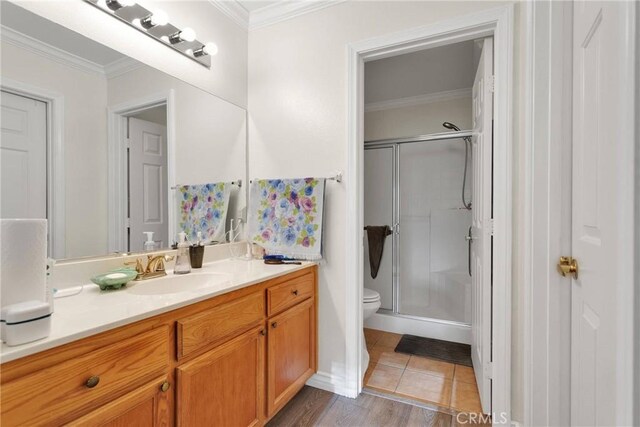 bathroom featuring tile patterned flooring, vanity, toilet, a shower with door, and crown molding