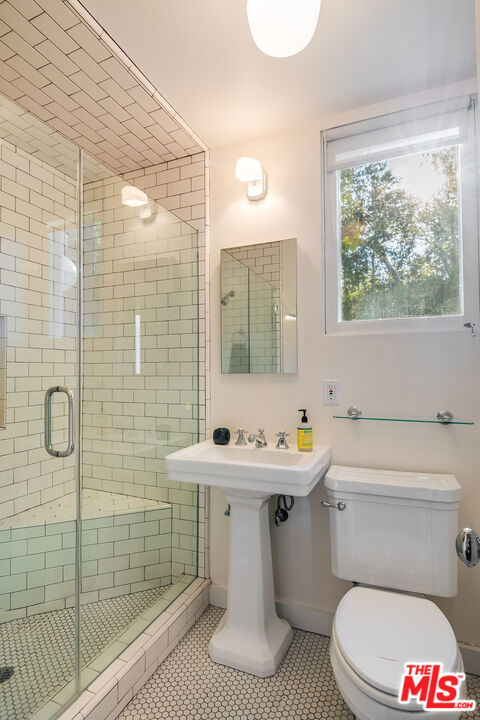 bathroom with tile patterned flooring, sink, an enclosed shower, and toilet