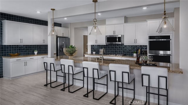 kitchen featuring white cabinetry, appliances with stainless steel finishes, and a kitchen bar