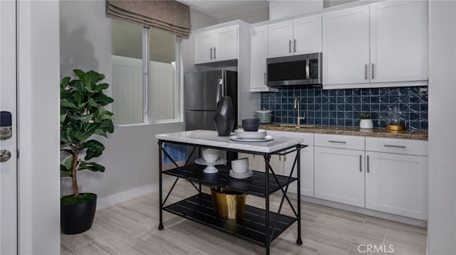 kitchen with stainless steel appliances, white cabinetry, sink, and decorative backsplash