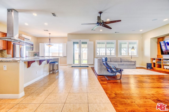 tiled living room featuring ceiling fan and french doors