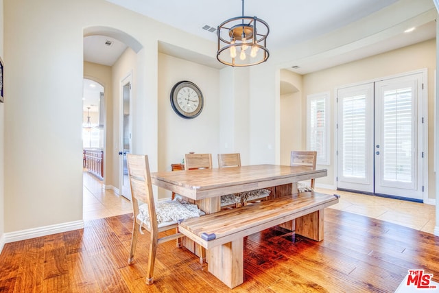 dining room with french doors, a chandelier, and light hardwood / wood-style flooring