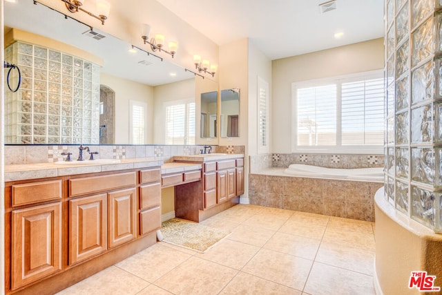 bathroom with tile patterned flooring, vanity, and a relaxing tiled tub