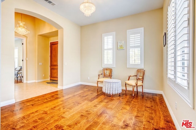 sitting room featuring wood-type flooring, plenty of natural light, and a notable chandelier