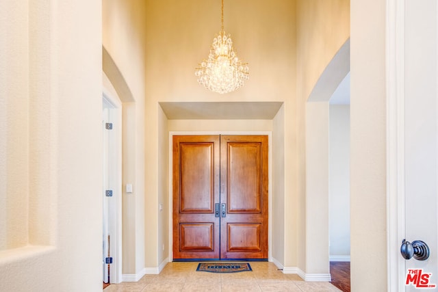 tiled entrance foyer with an inviting chandelier and a high ceiling