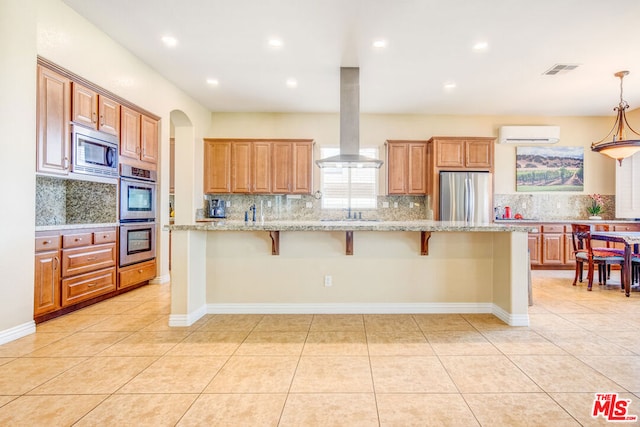 kitchen featuring a breakfast bar, island range hood, a kitchen island, stainless steel appliances, and light stone countertops